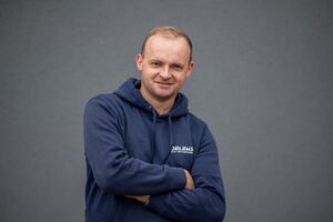 Porträtfoto - Slawomir in dunkelblauem Firmen-Kapuzenpullover