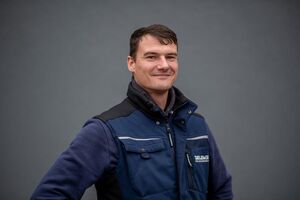 Porträtfoto - Nico in dunkelblauer Firmen-Weste mit blauem Pullover darunter