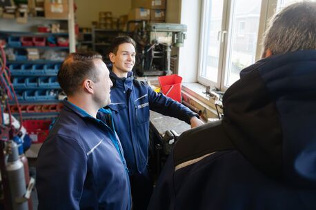 Ein erfahrener Mitarbeiter erklärt einem Auszubildenen die Funktion einer Kälteanlage.